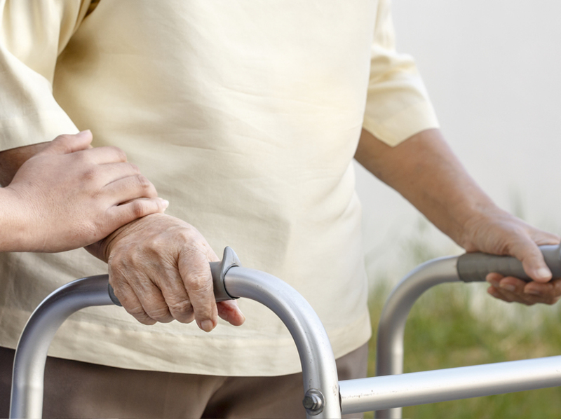 An image of an older lady with a walking frame who suffers from parkinsons disease.