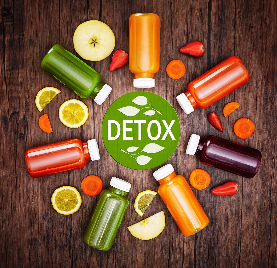 Bottles with delicious detox drinks and text detox on wooden bac