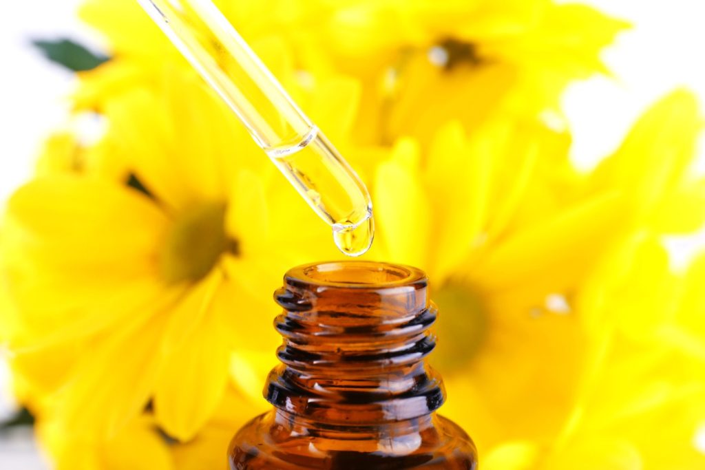 An appealing image of a homeopathic bottle in front of some pretty yellow flowers