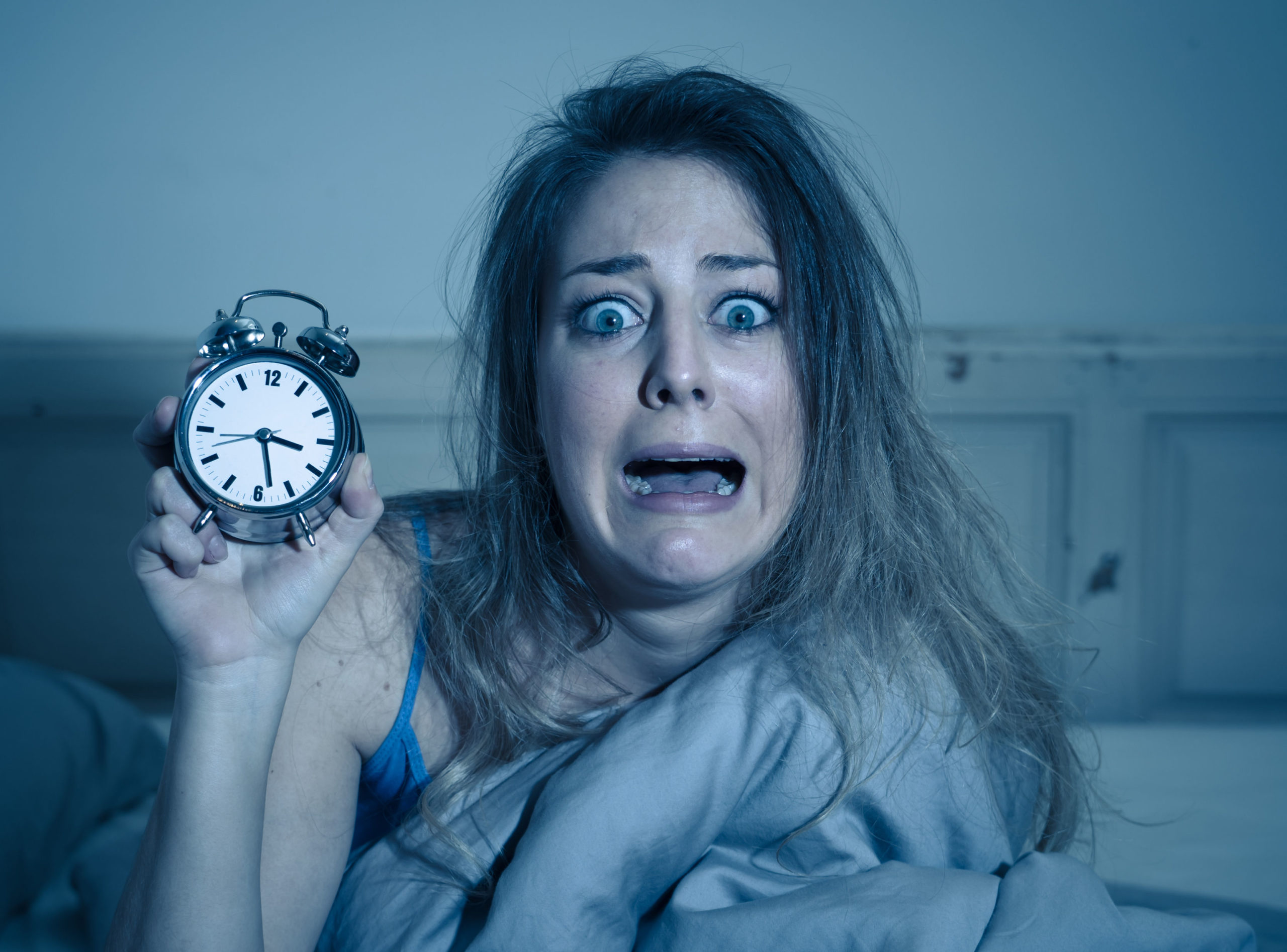 A distressed woman with a clock suffering from insomnia